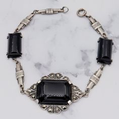 This Antique Art Deco sterling bracelet features three gorgeous onyx stones, the largest measuring 32x22mm, all set in sterling silver adorned with tiny marcasite stones. This bracelet weighs 11.9 grams and measures 7.25 inches in length. This bracelet has been repaired. It is in great antique condition with light wear and is marked as shown. Vintage Black Enamel Bracelet Jewelry, Vintage Black Enamel Bracelet, Vintage Silver Jewelry With Black Enamel, Victorian Silver Onyx Jewelry, Victorian Style Silver Onyx Jewelry, Art Deco Silver Onyx Jewelry, Formal Silver Jewelry With Black Enamel, Silver Jewelry With Black Enamel For Formal Occasions, Vintage Silver Onyx Jewelry