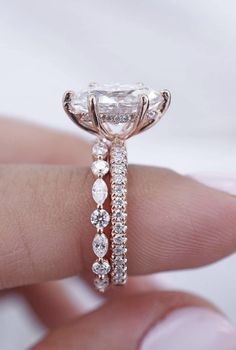 a woman's hand holding an engagement ring with a diamond band and side stones