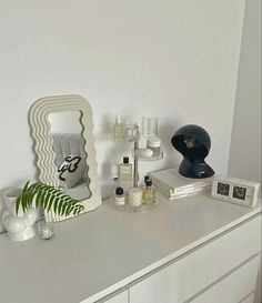 a white dresser topped with lots of different types of cosmetics and personal care items on top of it