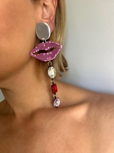 a close up of a person wearing earrings with lipstick and jewels on them