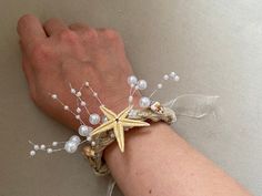 a person's arm with a starfish and pearls bracelet on top of it