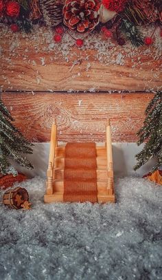 a wooden sleigh with pine cones and fir trees in the snow next to it