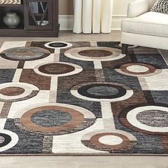 an area rug with various circles and shapes on it in a living room, next to a white chair