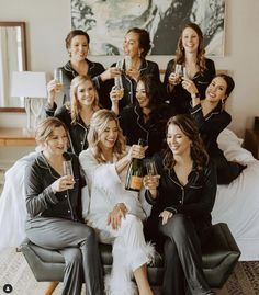 a group of women sitting on top of a bed toasting with wine glasses in their hands