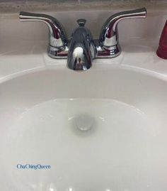 a white sink with chrome faucet and red soap dispenser