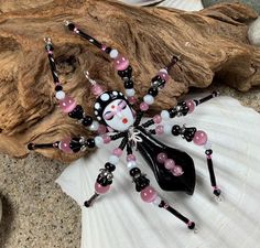 a black and white cat beaded necklace sitting on top of a shell next to a seashell