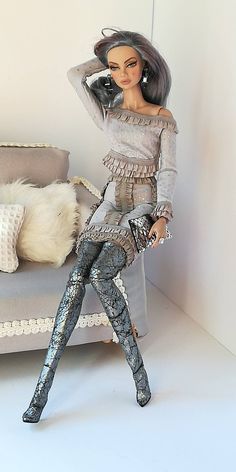 a doll is sitting on a couch with her legs up and holding a purse in front of her face