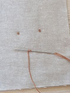 a piece of cloth with some thread on it and two pins in the middle that have been sewn together