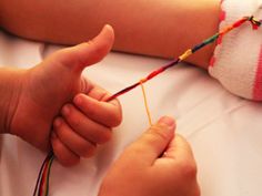 a child is playing with an object on the bed and someone is holding it up