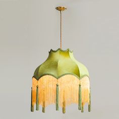 a green chandelier with fringes hanging from it's sides and a light fixture in the middle