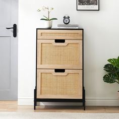 a wooden cabinet with two drawers next to a potted plant