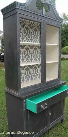 an old china cabinet painted black and green with damask stencils on the doors