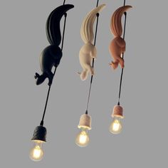 three different colored lights hanging from strings with cats on them and one light bulb turned upside down