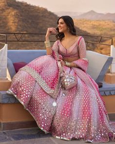 a woman sitting on top of a couch wearing a pink dress