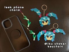 two pixel keychains are sitting next to a cell phone case on a table