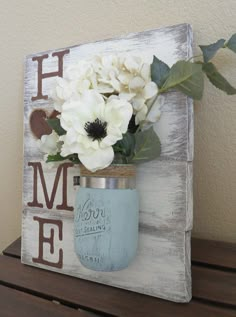 a mason jar with flowers in it sitting on top of a wooden shelf next to a wall