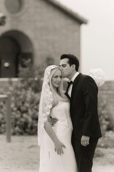 a bride and groom standing in front of a building