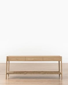 a wooden table sitting on top of a hard wood floor next to a white wall