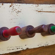 three wooden pegs are attached to the wall with red and green markers on them