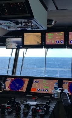 there are many monitors on the ship's control room wall as it looks out over the ocean