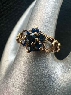 a gold ring with blue and white stones on it's side, sitting on top of a silver cloth