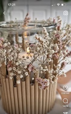 a vase filled with lots of flowers sitting on top of a white table next to candles