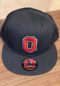 a black hat with the letter o on it sitting on top of a wooden table