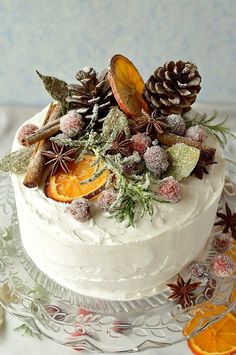 a white frosted cake topped with orange slices and pine cones