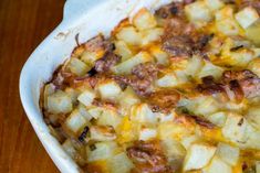 a casserole dish with potatoes and meat in it sitting on a wooden table