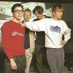 four young men posing for a photo in front of a wall with money on it