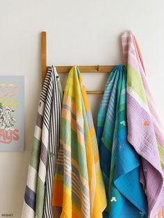 towels are hanging on a coat rack in front of a wall with an art print