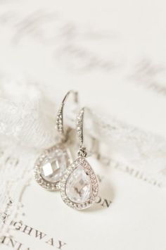 the bride's earrings are adorned with swarong and crystal stones, along with lace