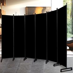 a room divider with four black poles in front of it and a painting on the wall