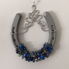 a horseshoe shaped necklace with blue beads and silver wire hanging from it's side