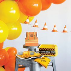 construction themed birthday party with orange and yellow balloons, construction zone cake topper, caution sign