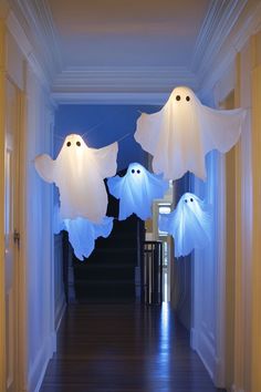 three ghost lights hanging from the ceiling in a hallway with wood flooring and white walls