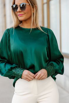 Shine bright and sparkle along the way in this stunning green satin blouse! With a boat neck, long sleeves, and shimmering sequin details at the cuff, you'll be the star of the show! Glamorous Green Evening Tops, Glamorous Green Top For Evening, Glamorous Green Tops For Evening, Green Blouse With Balloon Sleeves, Green Tops For Evening Party Season, Green Fitted Blouse With Balloon Sleeves, Satin Balloon Sleeve Top For Party, Elegant Satin Tops For Party Season, Green Sequin Tops For Fall