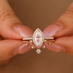 a close up of a person's hand holding a ring with a pear shaped diamond