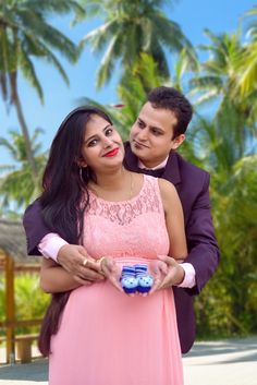 a man in a tuxedo and woman in a pink dress holding a toy car