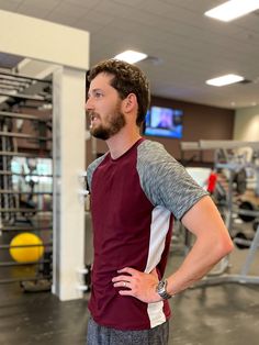 a man standing in a gym with his hands on his hips looking to the side