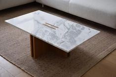 a white marble coffee table sitting on top of a rug in front of a couch