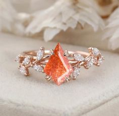 an orange diamond surrounded by white diamonds sits on a piece of cloth next to flowers