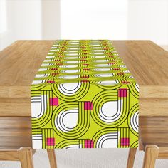 a wooden table topped with a green and pink patterned table cloth on top of it