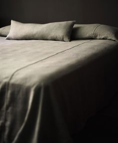 a bed with two pillows on top of it in a room that has dark walls