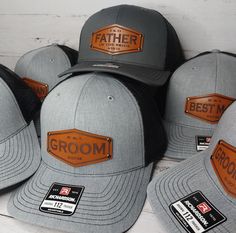 five hats with leather patches on them sitting next to each other in front of a white wall