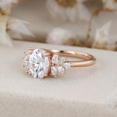 a rose gold engagement ring with an oval cut diamond surrounded by smaller round diamonds on top