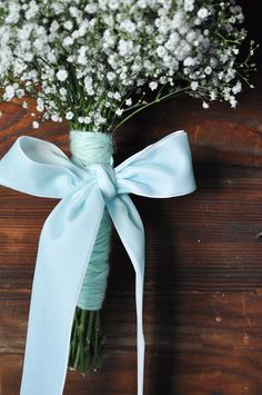 a bouquet of baby's breath tied to a wooden table with a blue ribbon