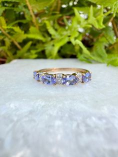 an image of a wedding ring with blue stones on the outside and green leaves in the background