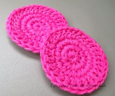 two pink crocheted coasters sitting on top of a white countertop next to each other