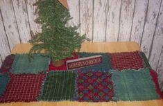 a small christmas tree sitting on top of a table next to a red and green blanket